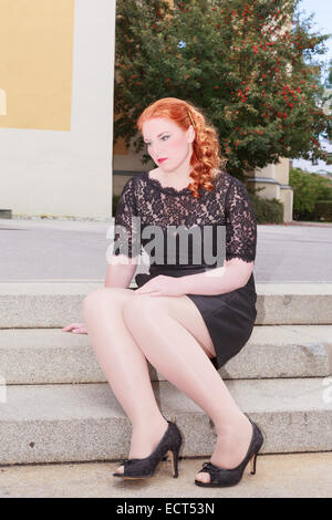 Chubby femme triste assis sur un escalier Banque D'Images