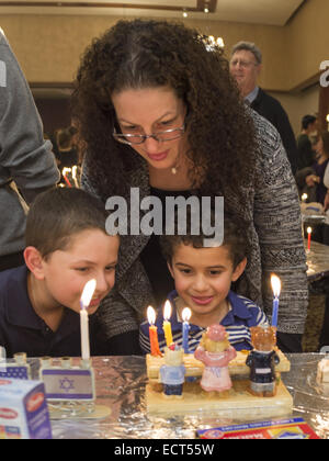 Merrick, New York, USA. Dec 18, 2014. CARRIE, BILITZKI BILITZKI et son fils Matthieu, 10 et Jacob, BILITZKI 5, regardez Jacob's trois ours menorah avec trois bougies allumées, au Centre juif de Merrick tente de reprendre le record du monde Guinness pour la plupart des Menorot allumé dans un endroit à la fois que la congrégation en 2011. Le troisième soir de Hanoukka, la 'Light Up the Night 2 - portant le bilan Accueil' event comprenait également une cérémonie de l'allumage des bougies dans le sanctuaire principal. Si la Menorah Lighing objectif d'au moins 1 000 lumière menorot a été manquée, et le dossier n'est pas w Banque D'Images