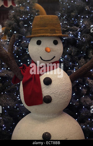 Une décoration de Noël Bonhomme de neige portant une écharpe avec un arbre derrière. Banque D'Images