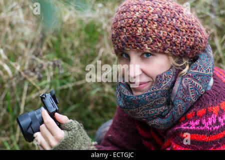 Fille blonde avec un appareil photo reflex smiling at the viewer Banque D'Images