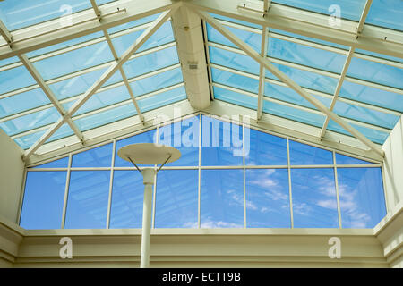 Ciel bleu vu par plafond de verre et le mur d'un immeuble moderne. Banque D'Images