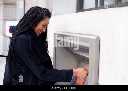 Jeune femme un retrait d'argent au guichet automatique. Banque D'Images