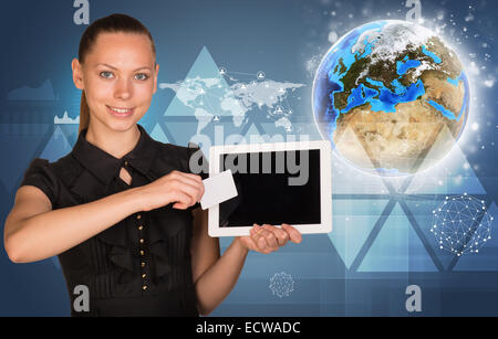 Belle businesswoman holding tablet PC. Globe, carte du monde avec d'autres éléments virtuels en toile Banque D'Images