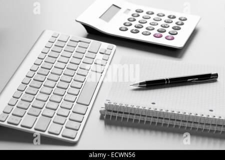 Bureau bureau avec clavier, stylo à bille, carnet à spirales et calculatrice avec profondeur de champ Banque D'Images