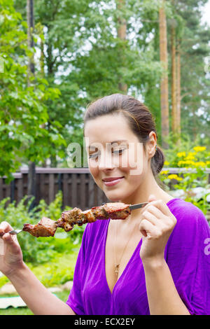 Pretty woman enjoying barbecue extérieur porc savoureux Banque D'Images