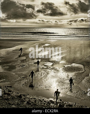 Silhouettes de surfers à pied avec des planches sur Perranuthnoe Beach Banque D'Images