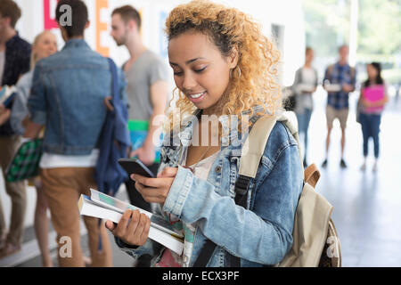 Female student standing in corridor et texting Banque D'Images