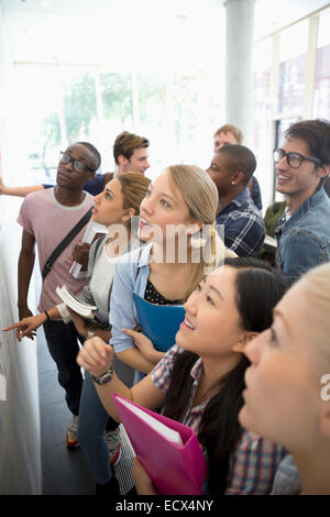 Portrait de groupe d'étudiants à la recherche à l'avis du conseil pendant les pauses