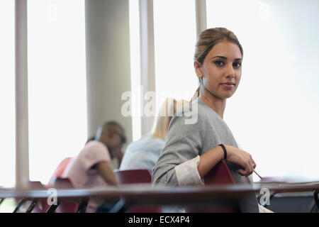 Female student looking at camera et assis à 24 au cours de lecture Banque D'Images