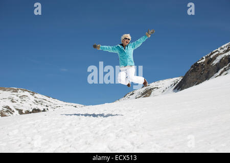 Femme exubérante qui saute dans la neige Banque D'Images