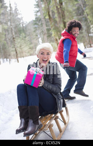 Homme Femme tirant avec gift on sled in snow Banque D'Images