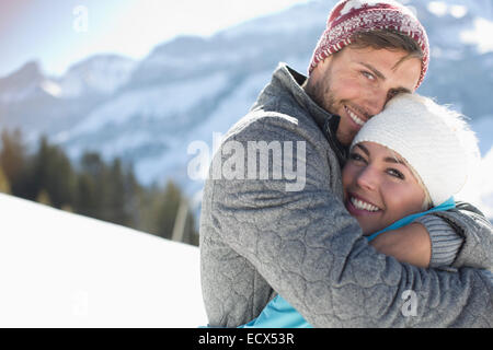Portrait of smiling couple hugging in snow Banque D'Images