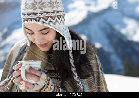 Smiling woman in Knit hat de boire un chocolat chaud à l'extérieur Banque D'Images