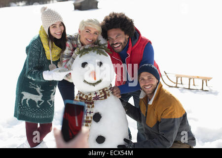 Les amis autour de snowman Banque D'Images