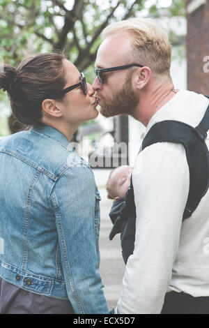 Lunettes de baisers et holding baby dans les rues de la ville Banque D'Images