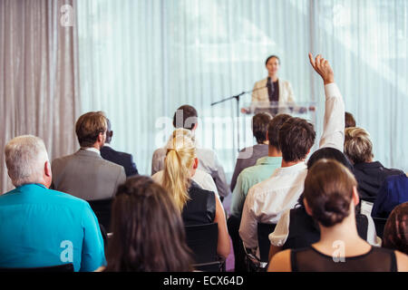 Businesswoman giving presentation dans la salle de conférence, les gens qui élèvent les mains Banque D'Images