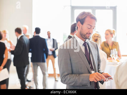 Mid adult businessman text messaging in office Banque D'Images