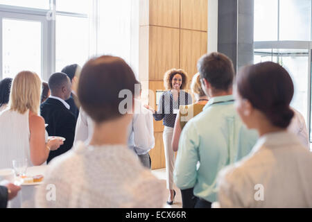 Les gens d'affaires standing in office hall holding plateaux avec des gâteaux et de l'eau potable Banque D'Images