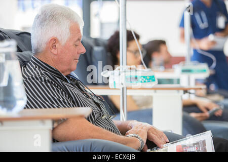 Senior man reading magazine en traitement médical en clinique externe Banque D'Images