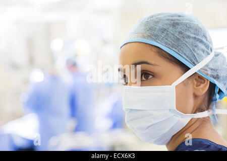 Portrait of surgical nurse wearing surgical cap et le masque dans le théâtre d'exploitation Banque D'Images