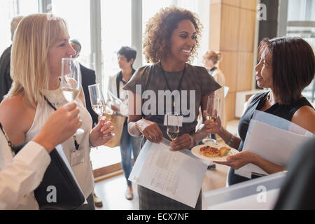 Businesswomen holding flutes de champagne et des documents lors d'interruption de la réunion Banque D'Images