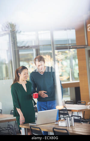 Business people using laptop in cafeteria Banque D'Images