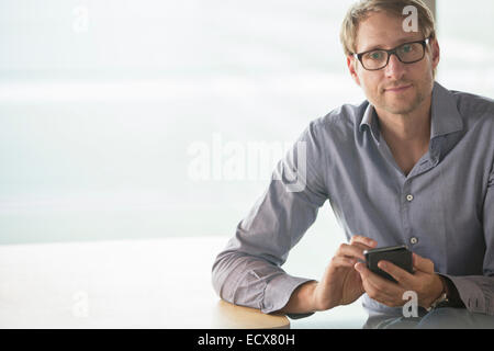 Businessman using cell phone at table Banque D'Images