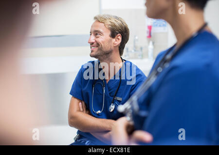 Milieu des profils médecin assis les bras croisés et smiling in hospital ward Banque D'Images