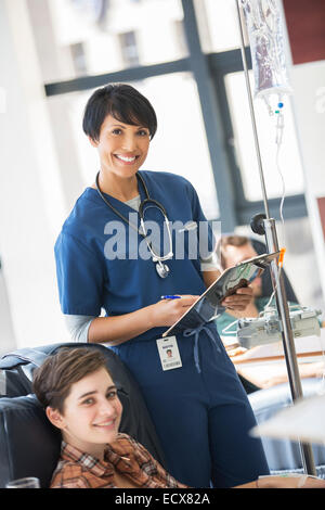 Femme médecin posant avec un jeune patient de recevoir des soins médicaux à l'hôpital ward Banque D'Images