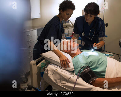 Deux médecins attending patient in hospital ward Banque D'Images