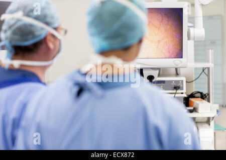Vue arrière de deux chirurgiens à à surveiller au cours de l'intervention en salle d'opération Banque D'Images