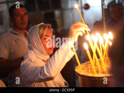 Bethléem, en Cisjordanie. Dec 21, 2014. Une adoratrice du chrétien au cours des bougies allume la messe du dimanche avant Noël à l'église de la nativité, dans la ville cisjordanienne de Bethléem, 21 décembre 2014. Les pèlerins chrétiens se préparaient à se rassembler dans la naissance de Jésus Christ en Cisjordanie pour célébrer Noël. (Xinhua/Luay Sababa) Credit : Xinhua/Alamy Live News Banque D'Images