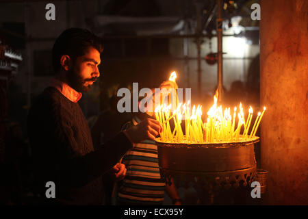 Bethléem, en Cisjordanie. Dec 21, 2014. Une adoratrice du chrétien au cours des bougies allume la messe du dimanche avant Noël à l'église de la nativité, dans la ville cisjordanienne de Bethléem, 21 décembre 2014. Les pèlerins chrétiens se préparaient à se rassembler dans la naissance de Jésus Christ en Cisjordanie pour célébrer Noël. (Xinhua/Luay Sababa) Credit : Xinhua/Alamy Live News Banque D'Images