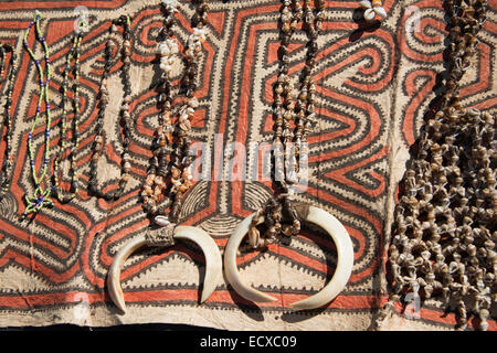 La Papouasie-Nouvelle-Guinée, Tufi. Colliers de coquillages avec défenses de sanglier sur tissu tapa traditionnels fabriqués à la main, fabriqués à partir de le papier mûrier. Banque D'Images