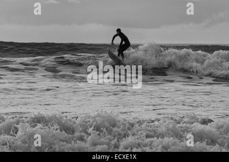 De bonnes conditions en mer permet à un internaute de rouler une bonne vague pour une longue course au nord du Pays de Galles, Porth Neigwl Banque D'Images