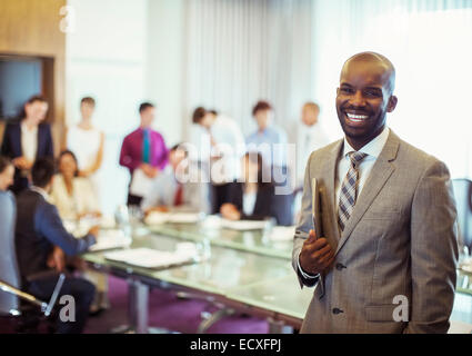 Portrait of smiling young man wearing costume et holding laptop dans la salle de conférence