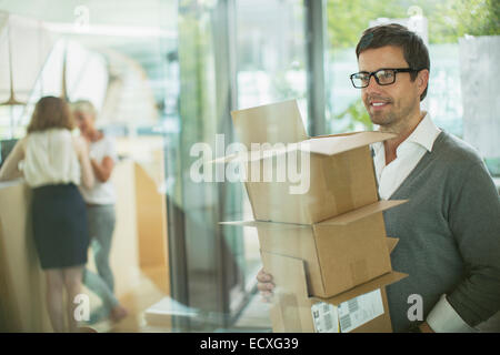 Businessman carrying cardboard boxes in office Banque D'Images