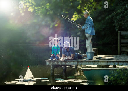 Garçon de pêche et Playing with toy voilier avec grand-père et au lac Banque D'Images