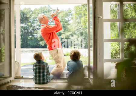 Grand-père à jouer de la trompette pour petits-fils Banque D'Images