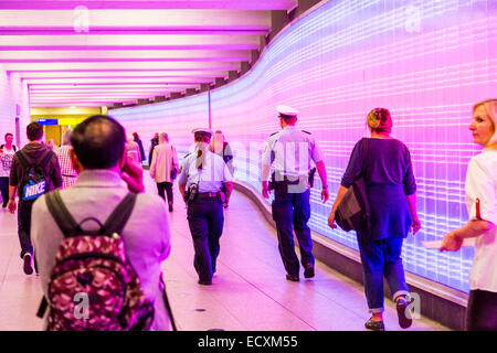 Les passagers dans un passage souterrain avec un mur de lumières, patrouille de police, Banque D'Images