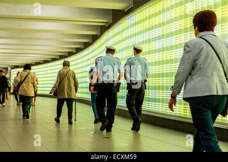 Les passagers dans un passage souterrain avec un mur de lumières, patrouille de police, Banque D'Images