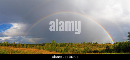 Un double arc-en-ciel lumineux sur arches un village champ. Banque D'Images