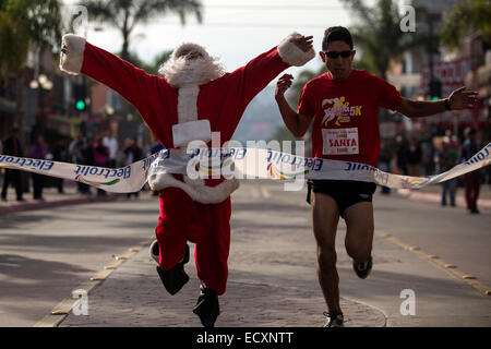 Tijuana, au Mexique. Dec 21, 2014. Les coureurs Carlos de los Angeles Jr. et Ulises Twiss, traverser la ligne d'arrivée à la fin de l'athletic course de Noël 'Run Santa Run', dans la ville de Tijuana, Baja California, dans le nord-ouest du Mexique, le 21 décembre 2014. Guillermo Arias/Xinhua/Alamy Live News Banque D'Images