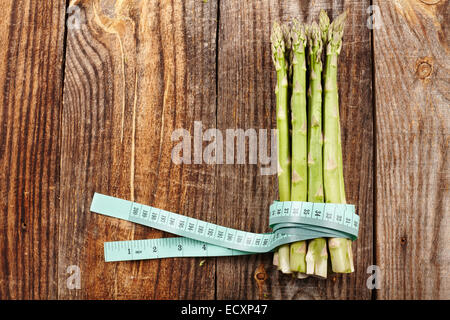 Concept de saine alimentation avec asperges fraîches et ruban à mesurer sur une planche en bois Banque D'Images
