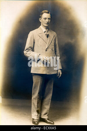 Vers 1920 portrait en studio sépia de Cyril Fairman, chef de groupe. Jeune homme en costume, debout, tenant une cigarette, regardant le spectateur. Banque D'Images