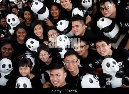 Kuala Lumpur, en Malaisie, 21 Dec, 2014. Les bénévoles poser pour les photographes avec la partie de l'article 1 600 pandas, au cours1600 Pandas World Tour en Malaisie le 21 décembre 2014 à Kuala Lumpur, Malaisie. 1600 pandas en papier créé par l'artiste français Paulo Grangeon sont exposés au Merdeka Square, les 1600 Pandas se rendra bientôt à plus de 15 sites importants en Malaisie. Credit : Asyraf Rasid/Pacific Press/Alamy Live News Banque D'Images