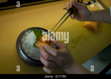 Détail d'un chef's hands, préparer le saumon avec des pinces dans 'o', un restaurant de sushi dans le centre de Londres. Banque D'Images