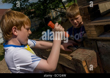 Les garçons utiliser claw hammer en aire d'aversion au risque a appelé la Terre sur Plas Madoc Estate, Ruabon, Wrexham, Wales. Banque D'Images