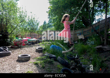 Girl balançoires sur rope swing en aire d'aversion au risque a appelé la Terre sur Plas Madoc Estate, Ruabon, Wrexham, Wales. Banque D'Images