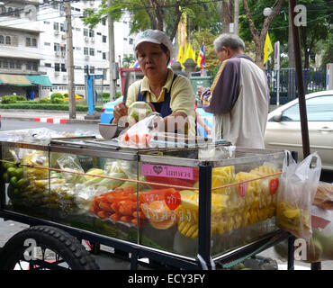 L'alimentation de rue, le vendeur de fruits, femme, au calage du vendeur à Bangkok. La Thaïlande, en Asie du sud-est. Banque D'Images